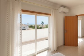 Una habitación con puerta corrediza de vidrio a un balcón, un armario de madera y un equipo de aire acondicionado.