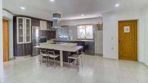 A modern kitchen with a central island, dark cabinetry, and a wooden door. - Villa Marazul Quinta Amizade w/ Sea View, Games room, Salt pool (Guia)