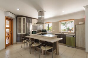 Una cocina moderna con una isla central, electrodomésticos integrados y vistas al exterior.