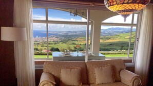 Une pièce avec un canapé placé face à une grande fenêtre, offrant une vue panoramique sur une vallée et une ville lointaine.