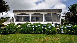 Un bâtiment moderne à l’extérieur blanc, doté de grandes fenêtres en arc de cercle et d’un toit plat.