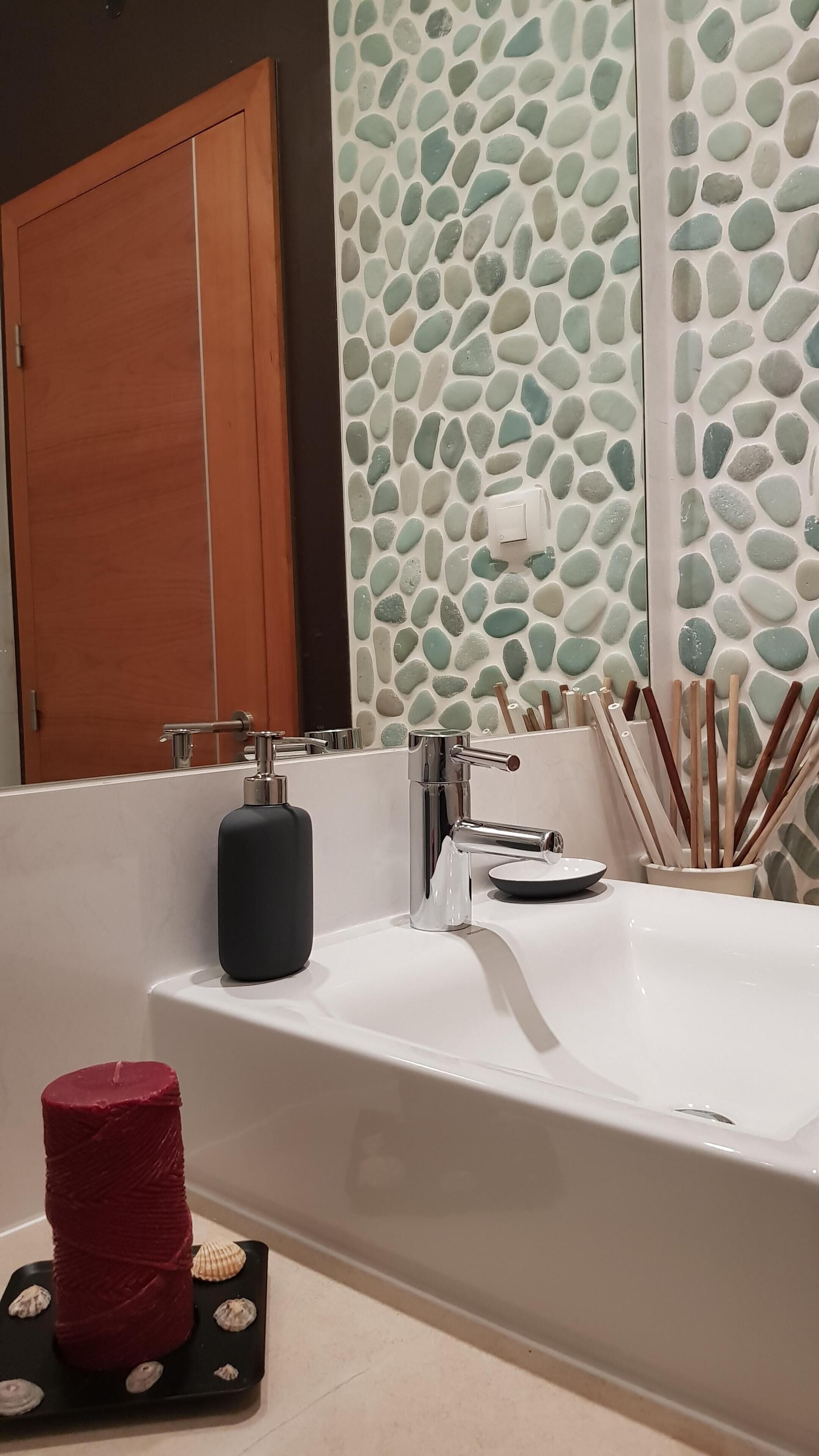 A bathroom with a white bathtub, a wooden door, and a wall with a pebbled texture.