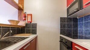Una cocina compacta con pileta, estufa y microondas.