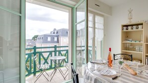 Un balcone con un tavolo apparecchiato per la cena, una sedia e un tavolino con una bottiglia e dei bicchieri.