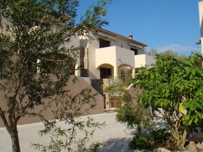 A building with a beige facade, stone accents, and a tiled roof. There are arched doorways and a balcony with a railing. - Apartment/ flat - CALVI (Calvi)