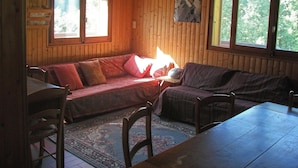 Ein gemütliches Blockhaus-Interieur mit Holzvertäfelung, einer Couch, einem Esstisch und einem Teppich.