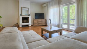 Una sala de estar con chimenea, televisor, sofá y una mesa.