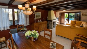 A dining area with a wooden table, chairs, a chandelier, and a fireplace. - Beautiful  villa for 14 guests with private pool, WIFI, TV, terrace and pets allowed (La Seu D'urgell)