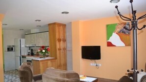 A living room with a sofa, a coffee table, and a TV mounted on the wall. - Bocanegra Rural Cottage for 10 people (Canicosa de la Sierra)