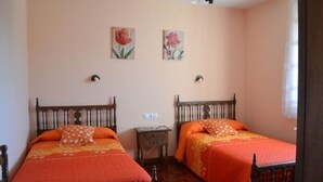 A bedroom with two wooden beds, each with an orange bedspread and matching pillows. There are two wall-mounted nightstands between the beds. - Bocanegra Rural Cottage for 10 people (Canicosa de la Sierra)