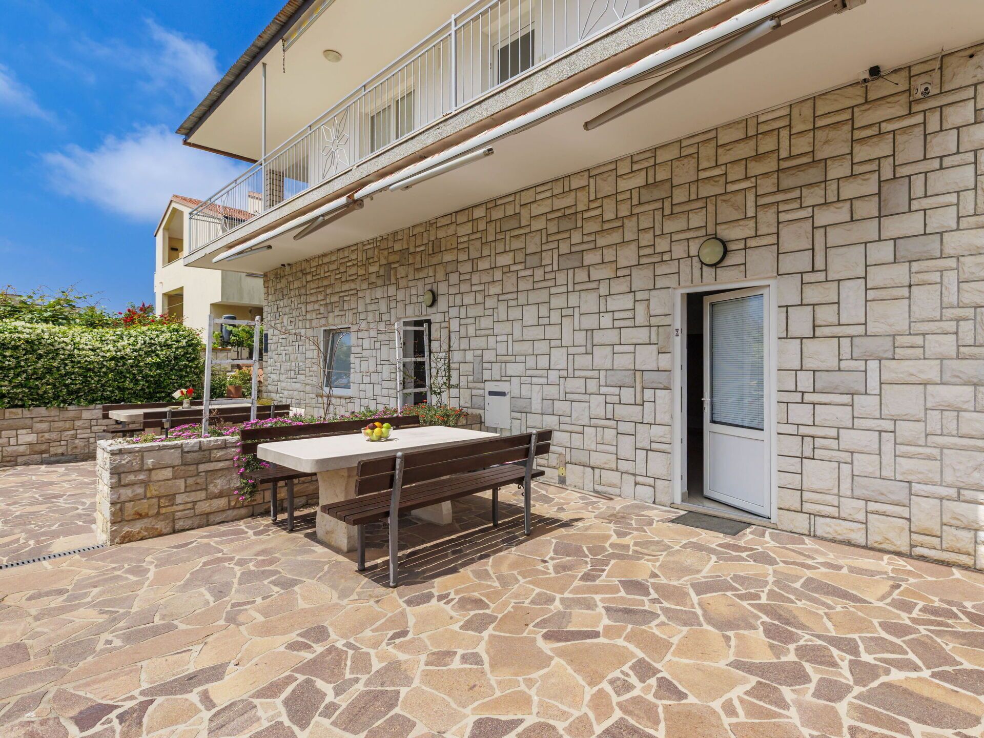 A stone patio with a table and benches, a door, and a stone wall.
