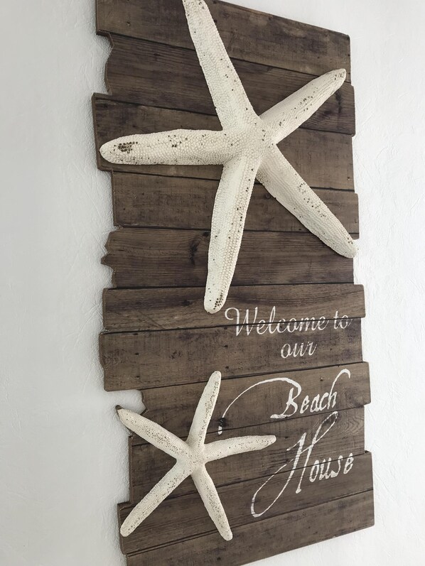 A wooden sign with a starfish and the text "Welcome to our Beach House".