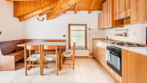 Una cocina con armarios de madera, una estufa y un comedor con un banco y sillas.