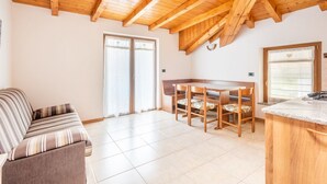 Una habitación acogedora con techo de madera, un sofá, una mesa de comedor con sillas y una zona de cocina.