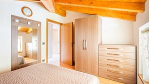 Un dormitorio con techo de madera, una cama grande, un armario y un espejo.