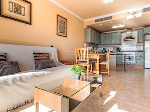 Un salon comprenant un canapé, une table basse en verre et un coin repas avec des chaises et une table.