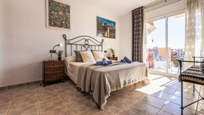 Ein Schlafzimmer mit Bett, Nachttischen, einem Schminktisch und einem Balkon mit Stühlen.