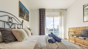 Ein Hotelzimmer mit Bett, Sofa, einem Gemälde und Blick ins Freie.