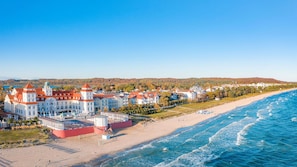 A coastal town with a prominent white building with red roofs, a beach, and a view of the sea.