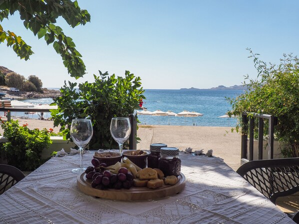 Una mesa dispuesta con una tabla de quesos, copas de vino y vista al mar.