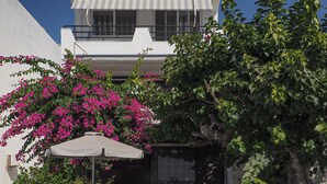 Un edificio de fachada blanca, con un balcón y un área de estar al aire libre techada, con una mesa y sillas.