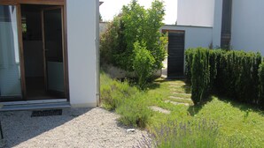 A residential garden with a gravel pathway, lavender plants, and a wooden door. - Central holiday home in the countryside for families with and without pets (Murnau am Staffelsee)