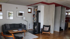 A modern living room with a sofa, a coffee table, a fireplace, and a bookshelf. - Central holiday home in the countryside for families with and without pets (Murnau am Staffelsee)