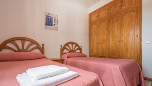 A room with two beds, each with a wooden headboard, and a large wooden wardrobe. - B&B Apartment near Caminito del Rey (Bermejo)