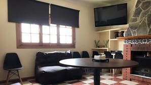 A living room with a sofa, a round table, a TV, and a fireplace. - B&B Apartment near Caminito del Rey (Bermejo)