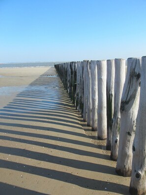 A wooden boardwalk leading to a beach with a clear sky.