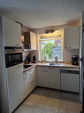 A compact kitchen with a built-in oven, a coffee maker, and a dishwasher.