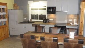 Una cocina moderna con comedor, que cuenta con una isla central, electrodomésticos integrados y un ventanal con cortinas estampadas.