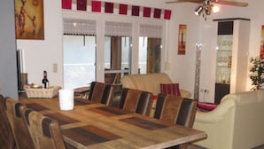 Un comedor con una mesa de madera y sillas de cuero, un sofá y un ventilador de techo.