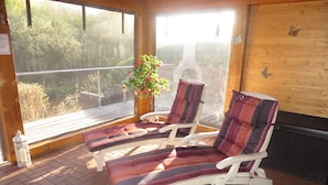 Un solárium con dos sillones de descanso, una planta en maceta y vistas al exterior.
