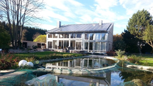 A modern house with a solar panel roof, a pond, and a garden. - Spacious semi-detached house in the east of Munich, with a view of the Alps (Markt Schwaben)