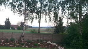 A pond with a wooden deck, surrounded by a brick wall and greenery. - Spacious semi-detached house in the east of Munich, with a view of the Alps (Markt Schwaben)