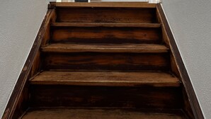 A wooden staircase with a handrail on the left, a mirror on the wall, and a coat rack with a bag. - Spacious semi-detached house in the east of Munich, with a view of the Alps (Markt Schwaben)