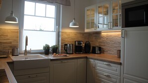 A modern kitchen with white cabinets, a stainless steel sink, a coffee maker, and a microwave.