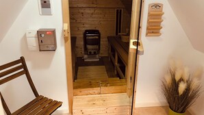 A wooden staircase leading to a loft area with a coffee machine, a bench, and a small table.