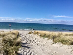A sandy beach path leading to the ocean, with a sign indicating a beach number.