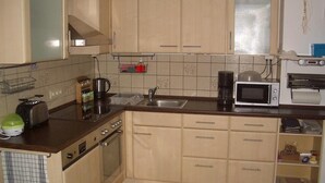 Une cuisine de taille réduite, dotée de meubles de rangement en bois, d’une cuisinière, d’un four à micro-ondes et d’un grille-pain.