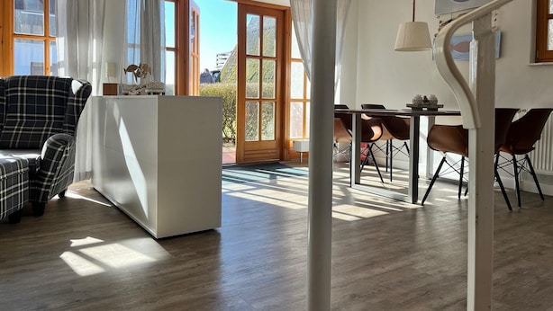 Ein modernes Wohnzimmer mit einer Couch, einem Esstisch mit Stühlen und einer Treppe mit Geländer.
