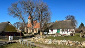 Ein traditionelles Gebäude mit einem Reetdach, Steinmauern und einem markanten Turm.