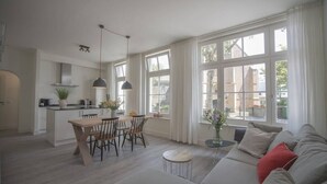 Una cocina moderna con comedor, ventanas amplias y una sala de estar con sofá y una pequeña mesa.