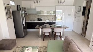 A modern kitchen with a dining area, a sofa, and a coffee table.