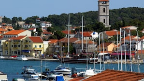 A marina with boats docked, a prominent tower, and colorful buildings with red-tiled roofs.
