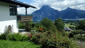 A house with a balcony overlooking a mountainous landscape and a lake.