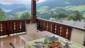 A dining area with a table set for four, overlooking a mountainous landscape.
