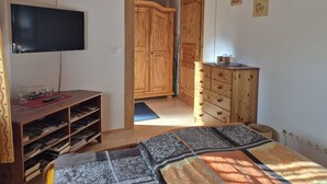 A bedroom with a bed, a TV, wooden furniture, and a clock on the wall.