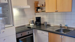 A modern kitchen with white cabinets, a black stove, a coffee maker, and a dishwasher.